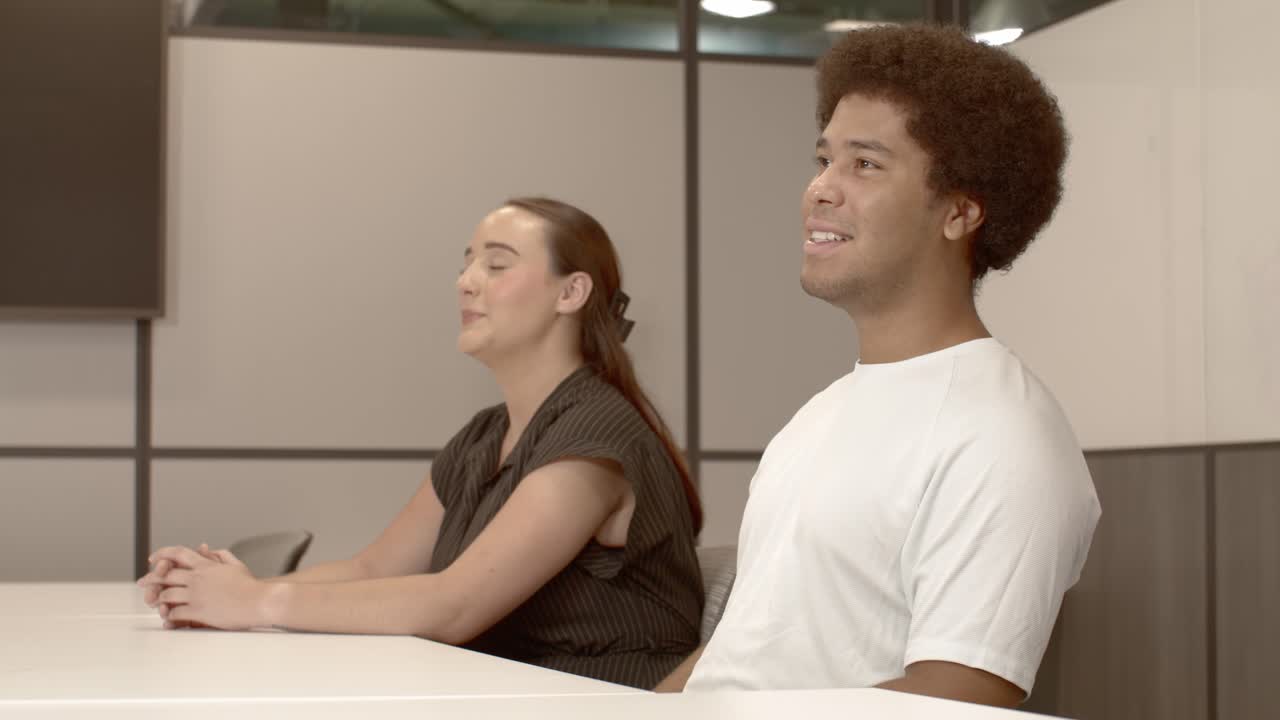 un hombre afroamericano de unos 20 años y una mujer caucásica de unos 20 anos hablando en una reunión de negocios con video estable.