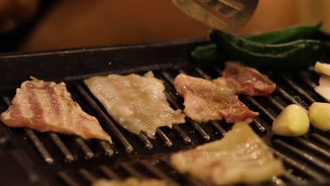 sizzling bacon strips and vegetables on a grill