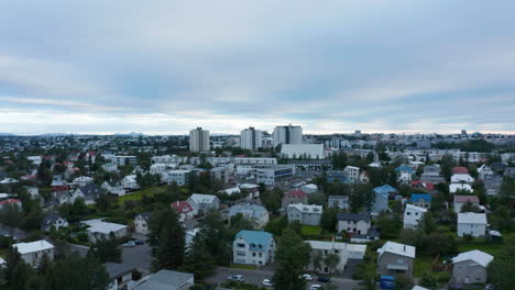 Fly-above-residential-borough-in-city.-Family-houses-with-gardens-and-trees.-Overcast-sky.-Reykjavik,-Iceland