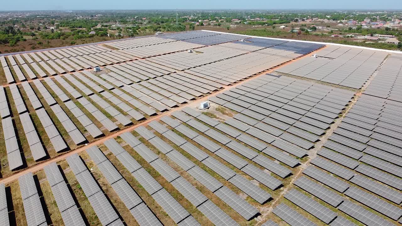Solar farm showing container inverters, solar panel arrays and cityscape with contrasting colors