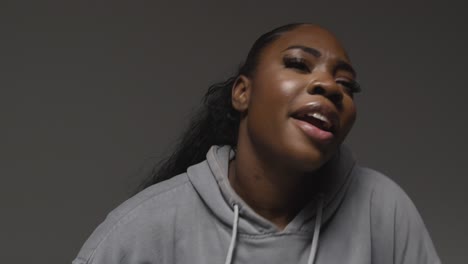 Studio-Portrait-Shot-Of-Young-Woman-Wearing-Hoodie-Dancing-With-Low-Key-Lighting-Against-Grey-Background-7