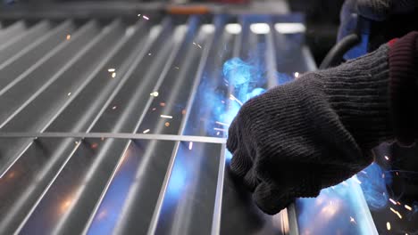 metal welder works with a steel welder in a factory with protective equipment