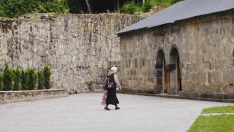 Old-woman-crossing-herself-while-walking-across-monastery-courtyard