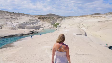 rear view of caucasian female walking sarakiniko beach in slow motion, milos, greece