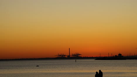 couple silhouetted against sunset at st kilda beach