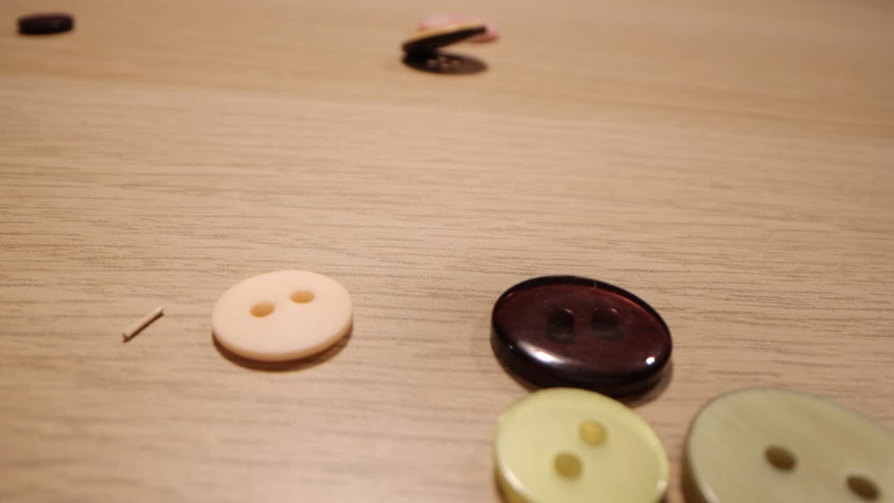 나무 테이블 위에 떨어지는 다양한 색의 바느질 버튼의 클로즈업. 패션 개념