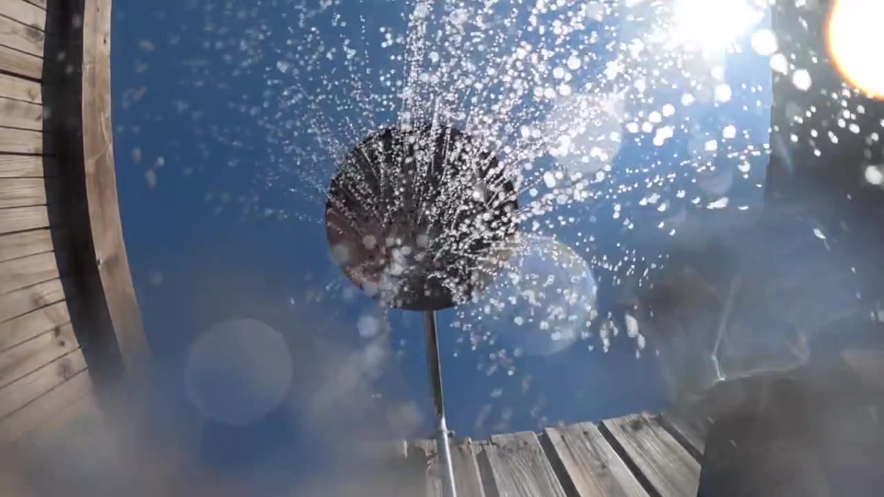 Gocce d'acqua che cadono e riflettono la luce del sole su un obiettivo della fotocamera, catturando l'effetto di schizzi rinfrescanti all'aperto.