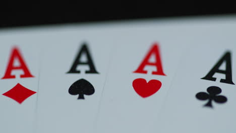 macro of a shot of playing cards with all four aces hearths diamonds space cross lying on an elephant while moving when the cards are splashed with water leaving a drop of detail