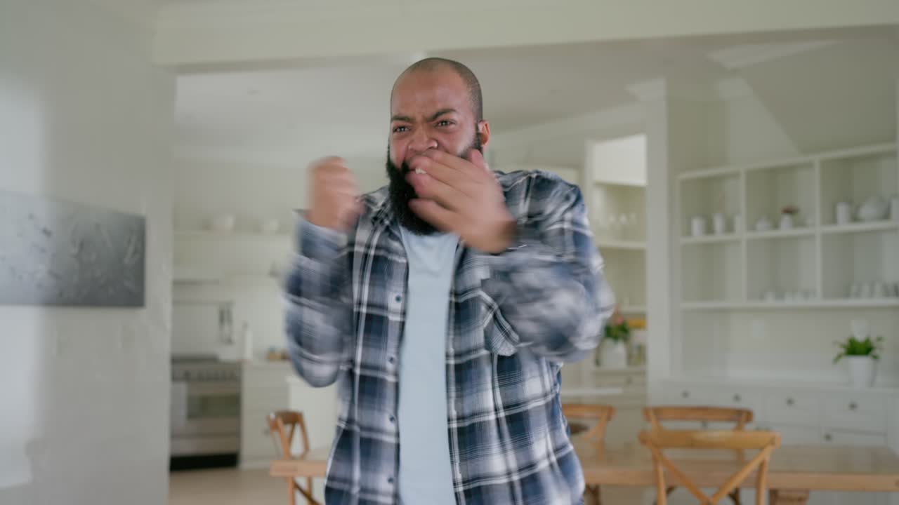 Adult African American man watching offscreen on couch, snacking popcorn, cheering, drinking bottle
