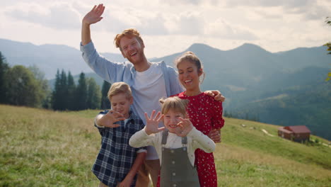 Familia-Riendo-Agitando-Las-Manos-De-Pie-En-La-Montaña.-Padres-Niños-Disfrutando-De-Vacaciones.