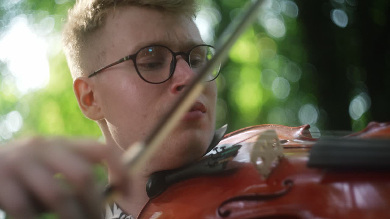 hombre caucásico de primer plano acariciando la cuerda del violín con arco, jugando al aire libre