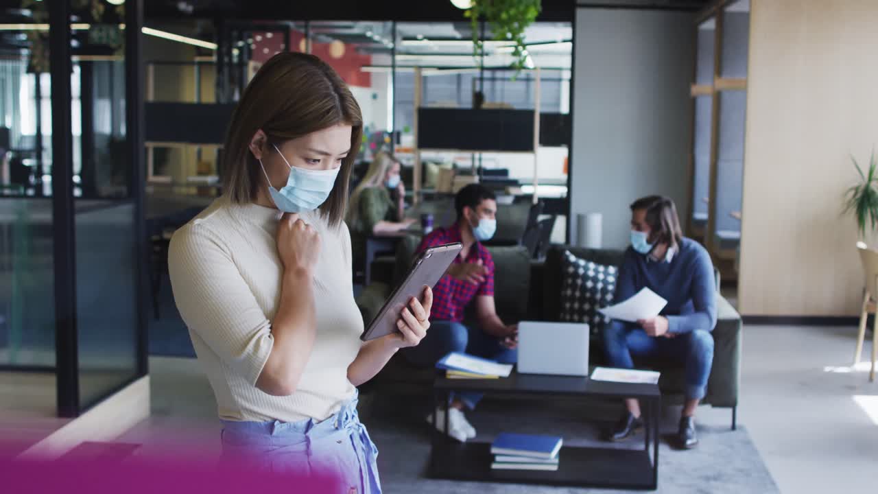 mujer de negocios asiática con máscara facial usando tableta digital oficina moderna
