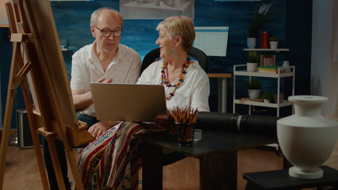Team of senior artists looking at artistic inspiration on laptop