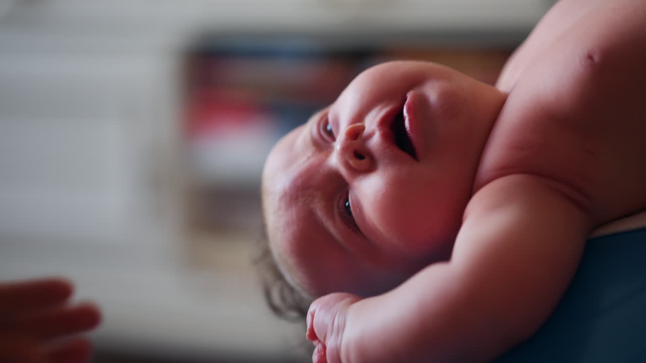 Baby placed on a stability ball while adults support the infant's body