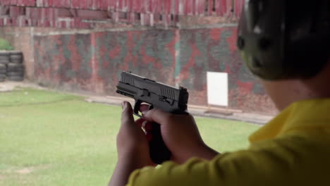 escenas en cámara lenta del arma disparando en un campo de tiro en la mano del hombre sujetar el arma con fuerza y apretar el gatillo