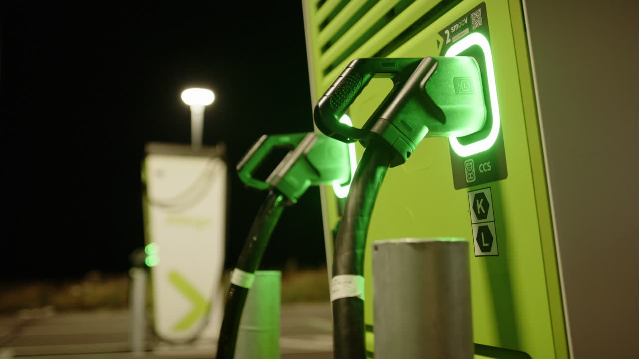 Allego EV charging stations at night illuminated green, smooth rack focus shot