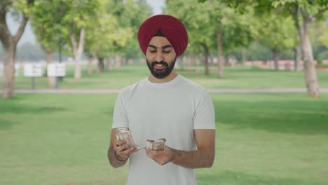 happy sikh indian man counting money in park