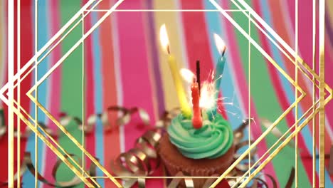 Animation-of-gold-lines-over-lit-birthday-candles-and-sparkler-on-birthday-cupcake