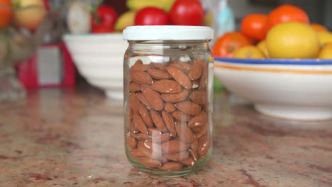 almendras sin cáscara a granel en un frasco de vidrio sobre una mesa de cocina