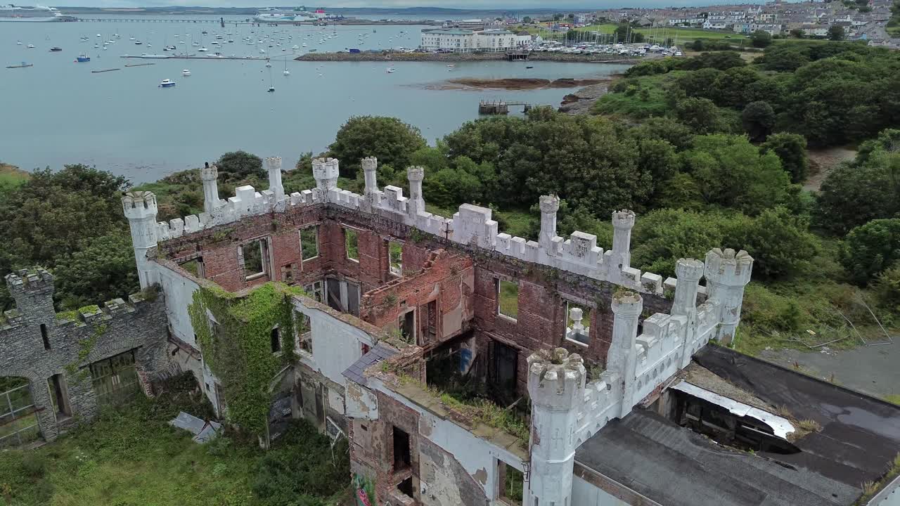 Abandoned mental health hospital remains aerial view circling overgrown coastal North Wales landmark