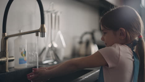 preschooler girl is washing hands in kitchen after cooking of before dinner cute little daughter is helping to cook