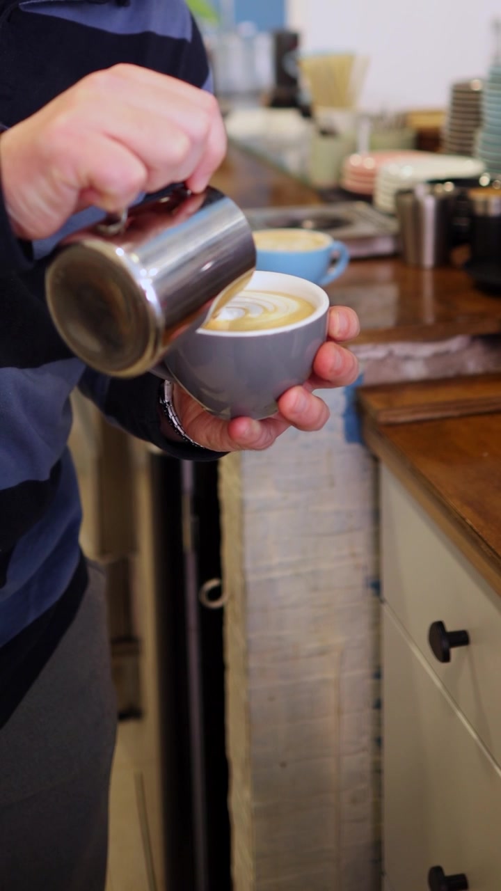 Barista che versa latte al vapore per creare l'arte del latte