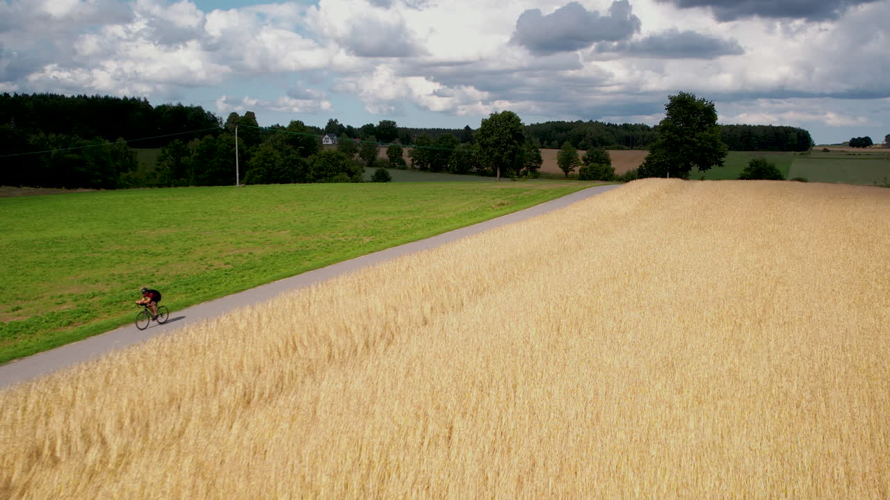 Cyclist on a narrow road between fields