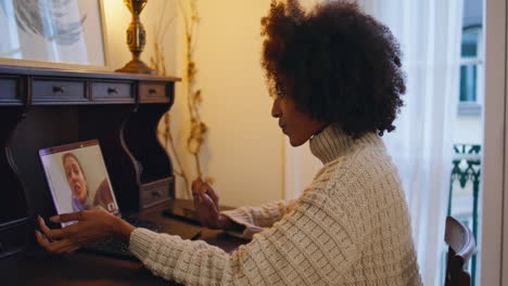 mujer feliz hablando video chat mesa portátil. mujer africana escuchando interlocutor
