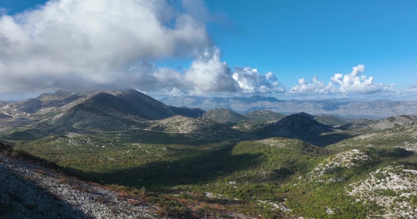 Veduta aerea di montagne aspre e una lussureggiante natura circostante vicino a Dubrovnik, Croazia. Il cielo blu nuvoloso crea ombre sulle montagne.