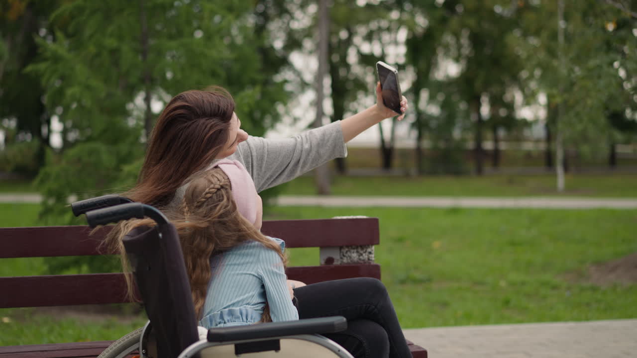 mujer disfruta haciendo selfies con niña en silla de ruedas