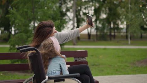 Woman-enjoys-making-selfies-with-little-girl-in-wheelchair