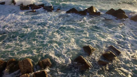 static slow-motion shot of waves crashing on a line of big rocks in syracuse, sicily (sicilia, italia)