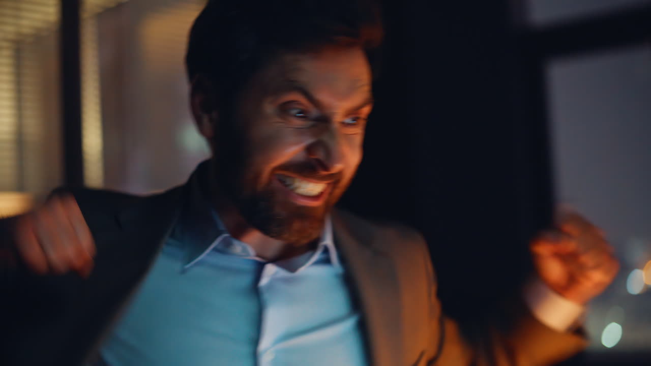 Surprised freelancer rejoicing success in laptop at evening office portrait