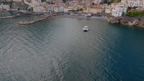 aerial: slow drone reveal shot of amalfi village in italy during sunset