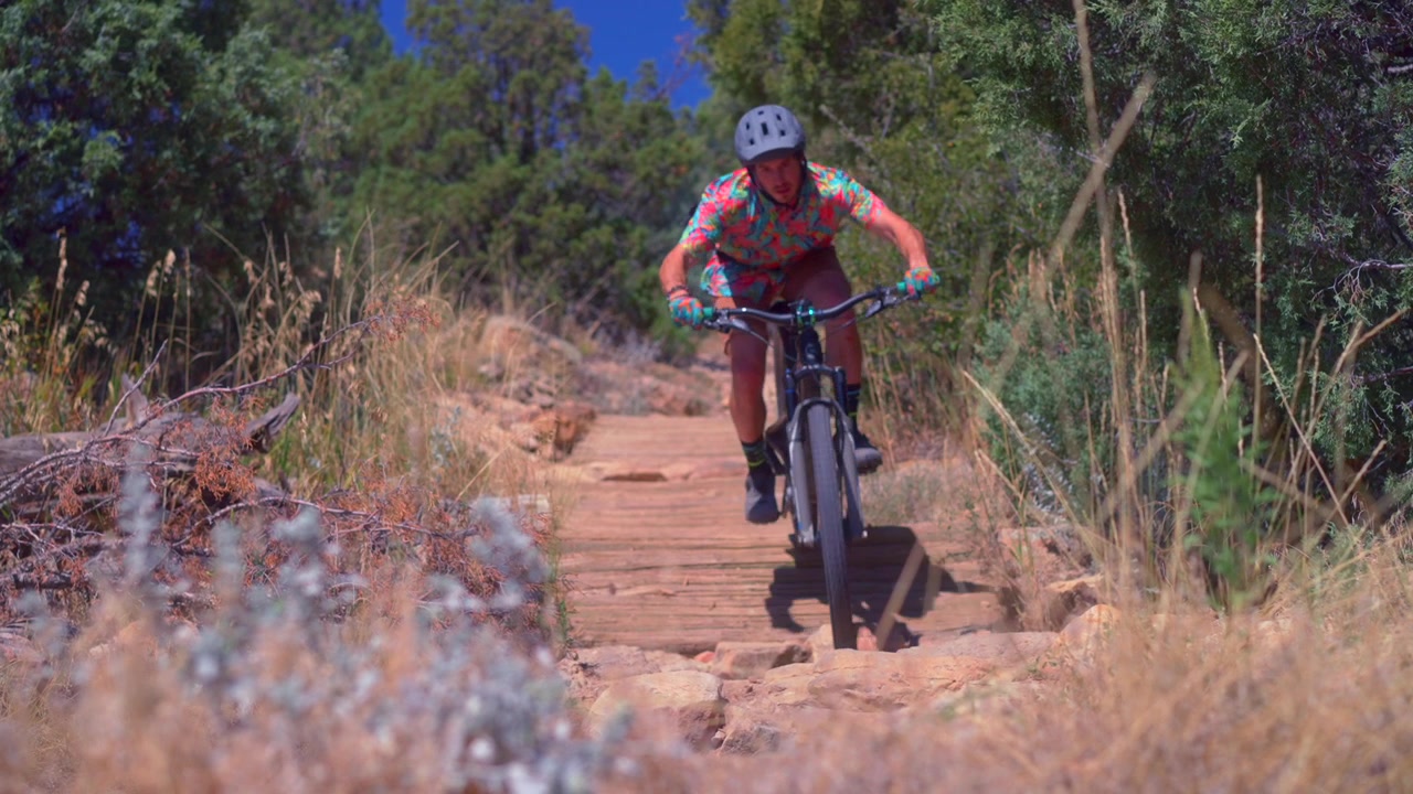 Homem adulto praticando mountain biking em Red Rocks, Morrison, Golden, Colorado. Ciclista em descida entre pedras, nas trilhas Dinosaur Ridge e Dakota Ridge. Esporte e fitness nos sopés de Denver, na cordilheira frontal, em um dia ensolarado. Close-up estático dos pneus da bicicleta.