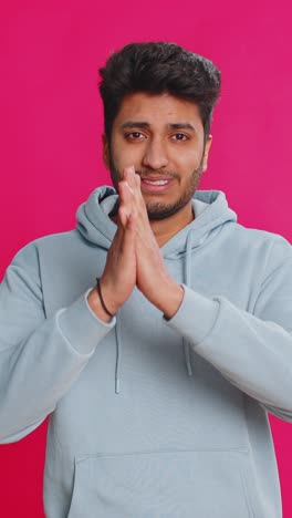 indian young man pleading begging hands together praying asking for help desperate hopeful indoors