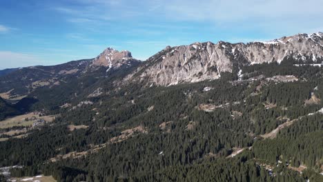 Standing-tall-against-the-blue-sky,-the-mountain-range-of-Tirol-Tannheimer-Tal,-Switzerland,-adorned-with-forests-stretching-to-the-valley-below,-showcasing-the-natural-allure-of-the-Swiss-landscape