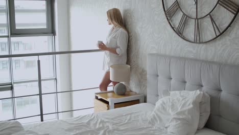 beautiful blonde woman standing next to a window in a loft apartment