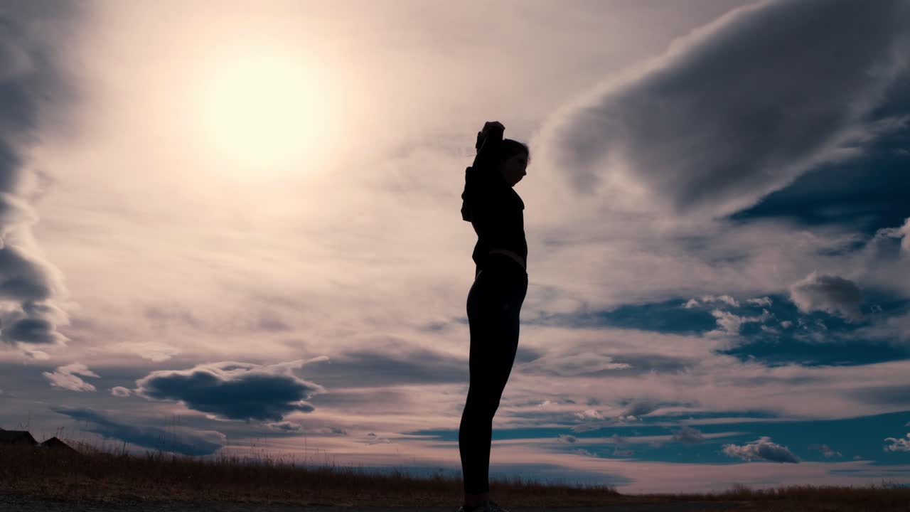 llamativo contorno de silueta negra de una corredora estirando los brazos contra un cielo dramático