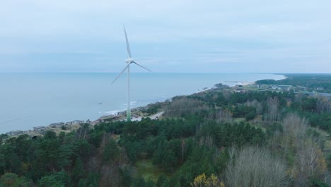 establishing aerial view of abandoned seaside fortification buildings at karosta northern forts on the beach of baltic sea in liepaja, overcast day, wind turbine, ascending drone shot moving forward