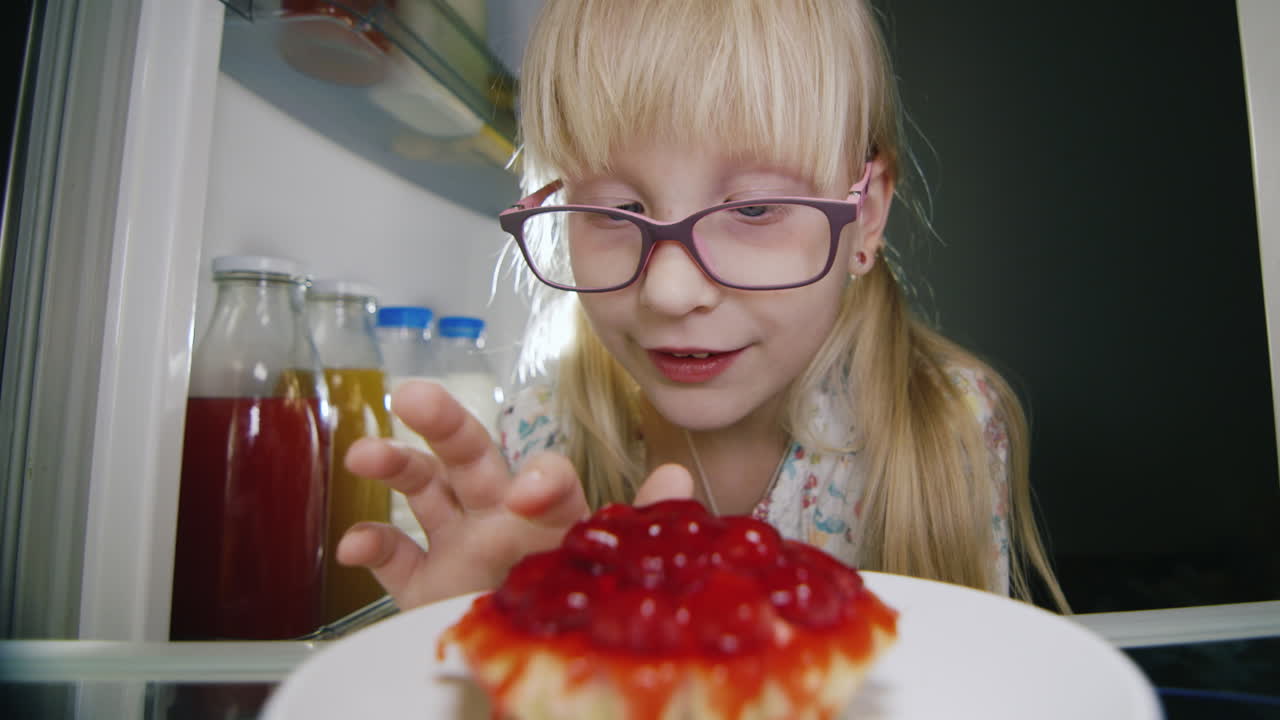una niña pequeña prueba en secreto el pastel en la nevera 1