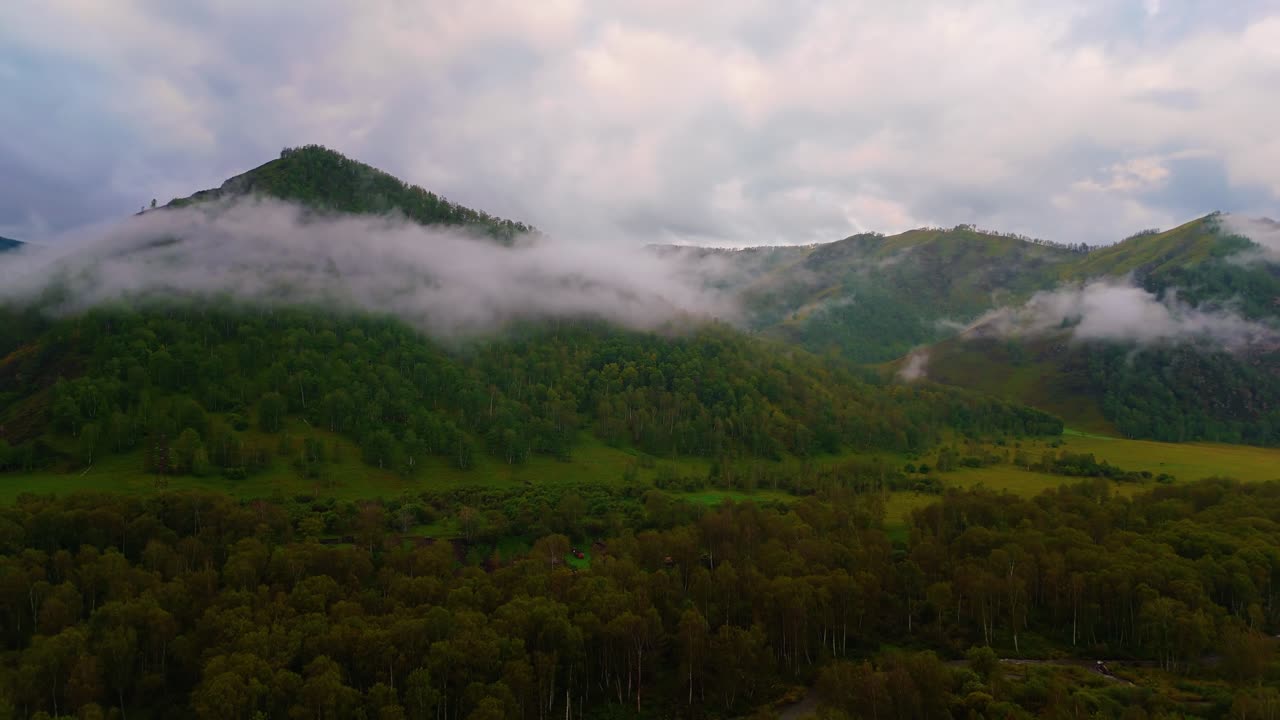 Drone flight over mountains in fog early in the morning in the Altai Mountains