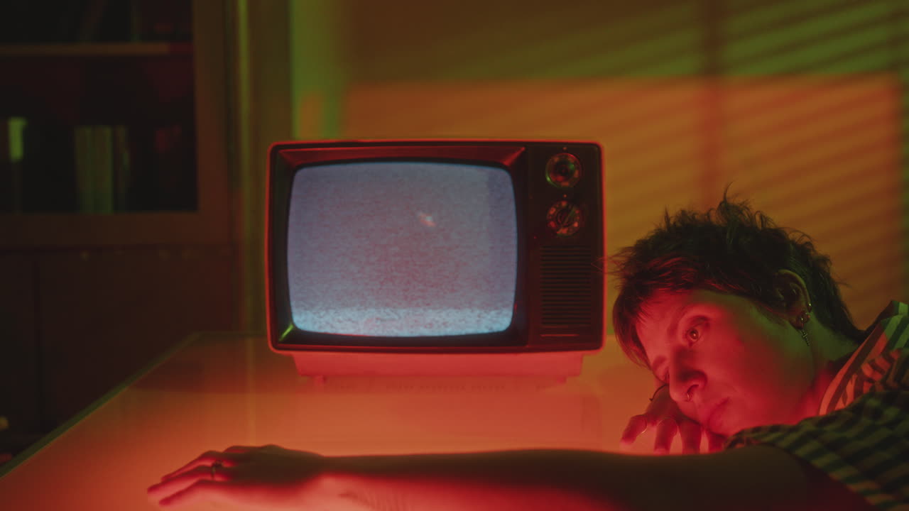 Mujer nostálgica apoyada en una mesa con una televisión analógica vintage mostrando ruido