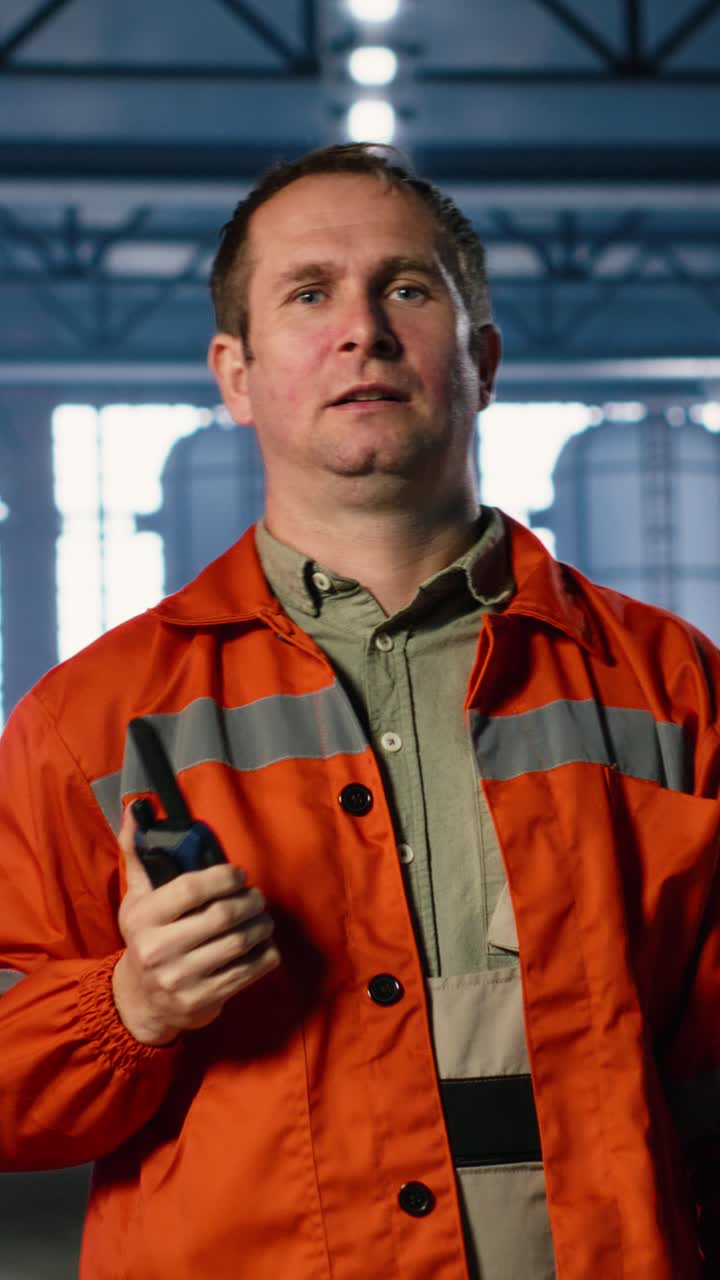 Vertical Video Heavy industry employee speaks into walkie talkie device in warehouse
