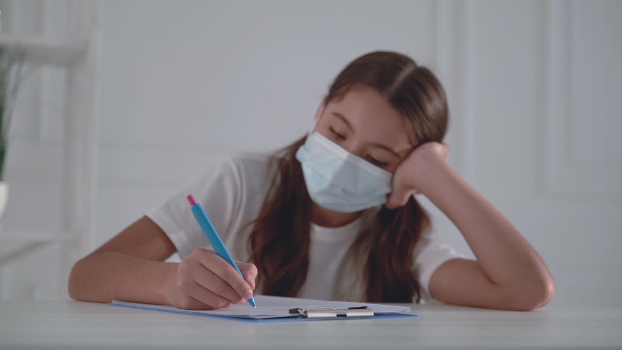 Little girl with medical face mask writing. Child filling out hospital form.