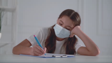 little girl with medical face mask writing. child filling out hospital form.