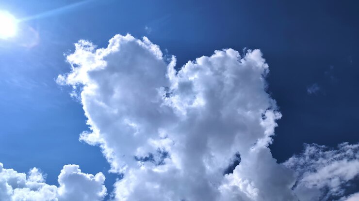 Heart shape clouds and sunshine in blue sky, view from bellow