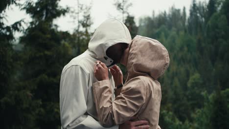 a happy couple, a guy and a girl, rejoice and hug during the rain against the backdrop of a mountain forest