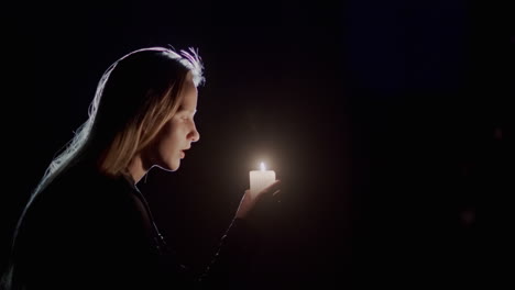 portrait of a child looking at a candle burning in the dark. side view