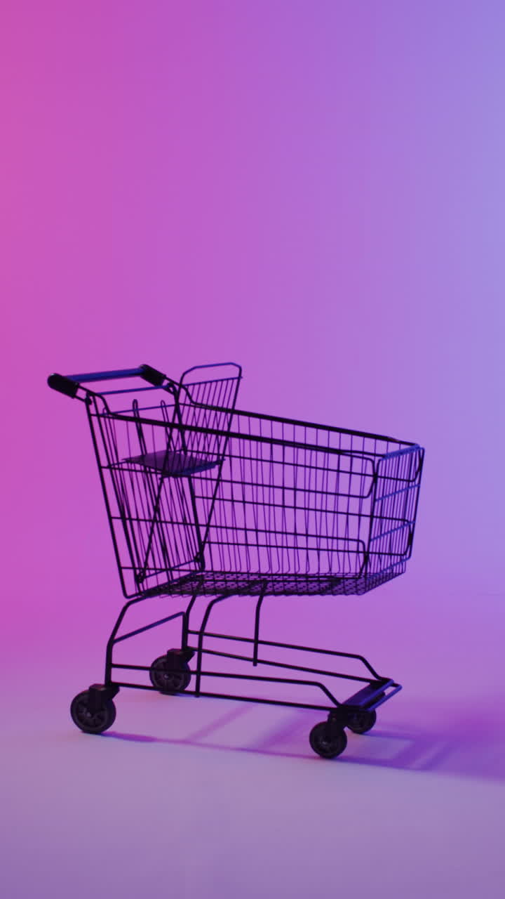Vertical video of shopping trolley with copy space over pink neon background